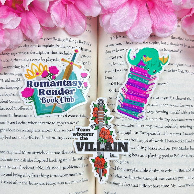 May include: Four colorful stickers featuring book-themed illustrations. The first sticker features a sword and roses with the text "Team whoever the VILLAIN is..." The second sticker features a dragon reading a stack of books. The third sticker features a stack of books with the text "Romantasy Reader Book Club". The fourth sticker features a sword and roses with the text "Team whoever the VILLAIN is..."