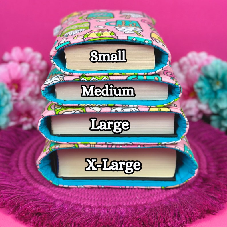 May include: Pink book sleeves with a colorful pattern, each labeled with a size: Small, Medium, Large, and X-Large. The sleeves have a turquoise lining and are stacked on a purple mat.