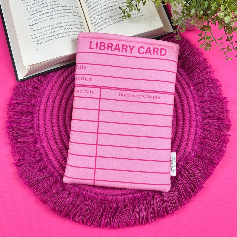 May include: Pink library card book sleeve with a white border and the text "LIBRARY CARD" printed in black. The sleeve has blank lines for "Title", "Author", "Due Date", and "Borrower's Name".