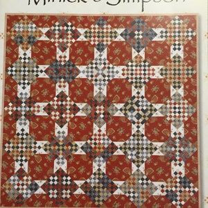 May include: A quilt with a Chippewa Nine Patch design. The quilt features a red background with a paisley pattern. The patchwork design incorporates squares in various colors, including white, blue, black, and brown. The text "Minick & Simpson" and "Chippewa Nine Patch" are visible.