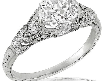 May include: A vintage engagement ring with a large, round, brilliant-cut diamond set in a delicate, filigree platinum band. The band is adorned with smaller diamonds.