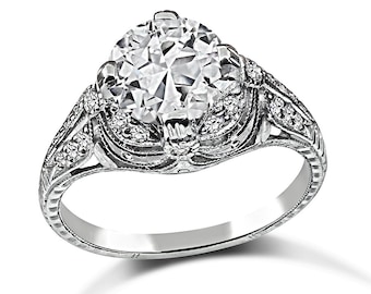 May include: A vintage-style engagement ring with a large, round, clear diamond set in a filigree band.