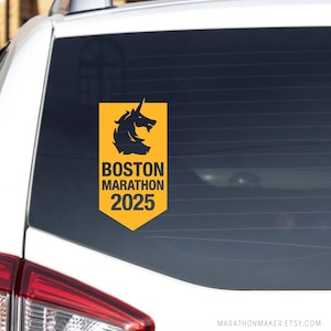 Puede incluir: Una pegatina amarilla y negra con una cabeza de unicornio y el texto "BOSTON MARATHON 2025".