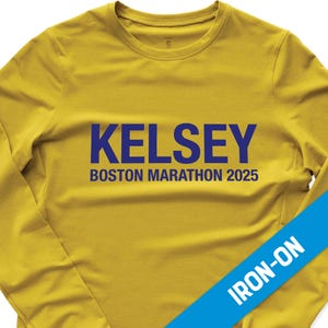 May include: Yellow long-sleeve shirt with a blue iron-on design that says "Kelsey Boston Marathon 2025".