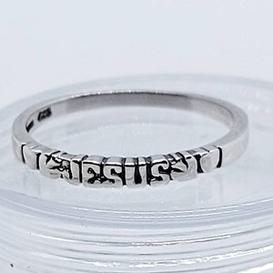 Può includere: Un anello d'argento con la parola "GESÙ" scritta in lettere in rilievo.