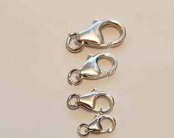 Pode incluir: Quatro fechos lagosta prateados de tamanhos variados estão dispostos em linha vertical. Cada fecho possui um mecanismo de mola e um pequeno anel para fixação. Os fechos são feitos de metal brilhante e refletivo.