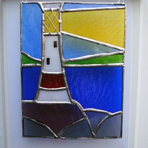 May include: A stained glass window featuring a white lighthouse with a red band, against a blue and green seascape. The sky is yellow and blue.
