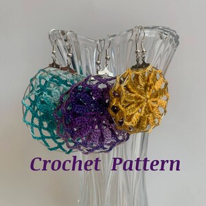 May include: Three crochet earrings in teal, purple, and gold hang from a glass vase. The earrings have a circular design with intricate openwork patterns. The text "Crochet Pattern" is displayed in a purple font.