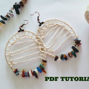 May include: A pair of crocheted hoop earrings with colorful gemstone accents. The earrings are made with white thread and have a delicate, openwork design.  PDF TUTORIAL.