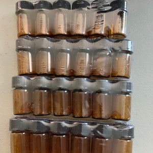 May include: A package of twenty-four small amber glass bottles with black screw-on lids. The bottles are packaged in a clear plastic wrap.