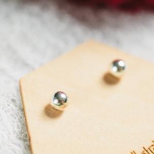 May include: A pair of silver stud earrings on a hexagonal display card with the text "the illustratorist" and "theillustratorist.etsy.com".