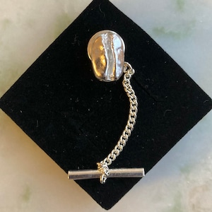 Può includere: Fermaglio per cravatta in argento con un design a forma di chicco di caffè e una catena.