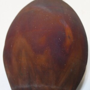 May include: A brown ceramic vase with a rounded body and a narrow neck. The vase has a mottled, textured surface with shades of brown, orange, and purple.