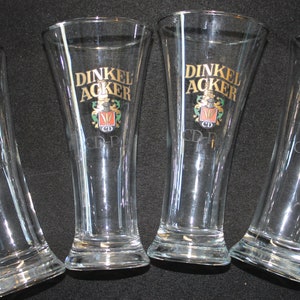 May include: Four clear glass beer glasses with a gold logo that says "Dinkel Acker" and a crest with a "CD" inside.