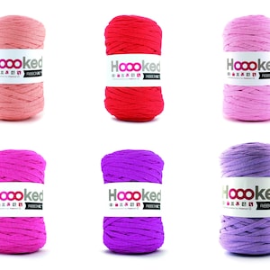 Könnte beinhalten: Sechs Spulen Hoooked Ribbon XL Garn in verschiedenen Farben: Koralle, Rot, Rosa, Pink, Lila und Lavendel.