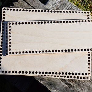 Könnte beinhalten: Drei Holz-Webrahmen mit schwarzen Kreisen an den Rändern. Die Bretter sind übereinander gestapelt.