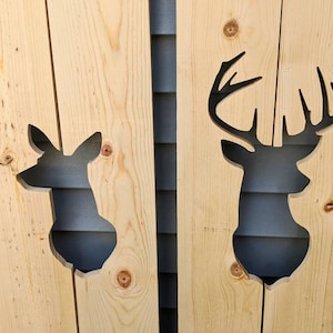 May include: Two wooden panels with cutout silhouettes of deer heads. The panels are light brown and the deer silhouettes are black.