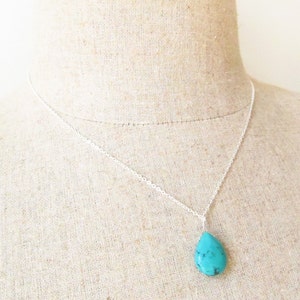 May include: A silver chain necklace with a turquoise teardrop pendant.