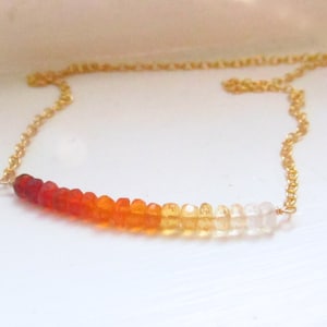 May include: A gold chain necklace with a graduated row of orange, yellow, and white gemstone beads.