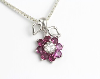 May include: A silver necklace with a pendant featuring a flower design with pink and white gemstones.
