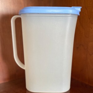 May include: A clear plastic pitcher with a light blue lid and a handle. The pitcher is empty.