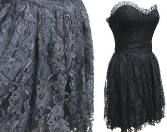 May include: A black lace strapless dress with a sweetheart neckline. The dress has a fitted bodice and a full skirt.