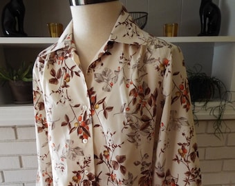 Puede incluir: Una camisa de manga larga con botones, fondo crema y estampado floral marrón y naranja.