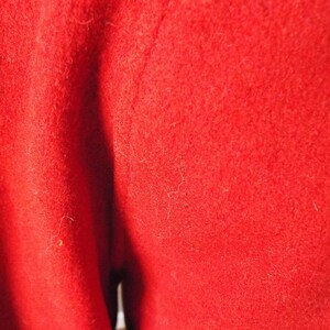 May include: Close-up of a red fabric with a smooth texture. The fabric is folded in half, creating a crease down the center.