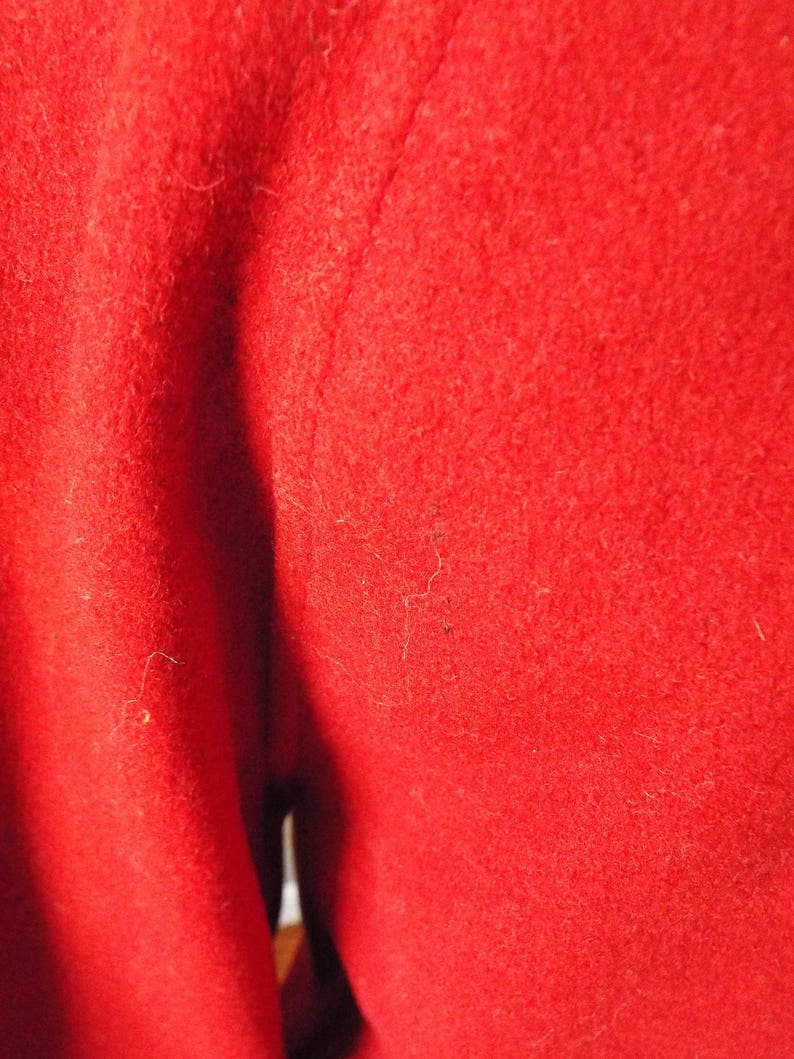 May include: Close-up of a red fabric with a smooth texture. The fabric is folded in half, creating a crease down the center.