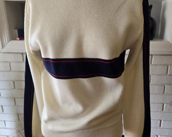 May include: A white sweater with a navy blue and red stripe across the chest and navy blue stripes on the sleeves.