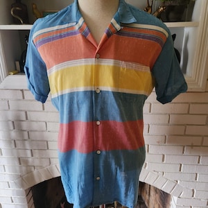 May include: A blue, orange, yellow and white striped short-sleeved button-up shirt with a collared neckline.