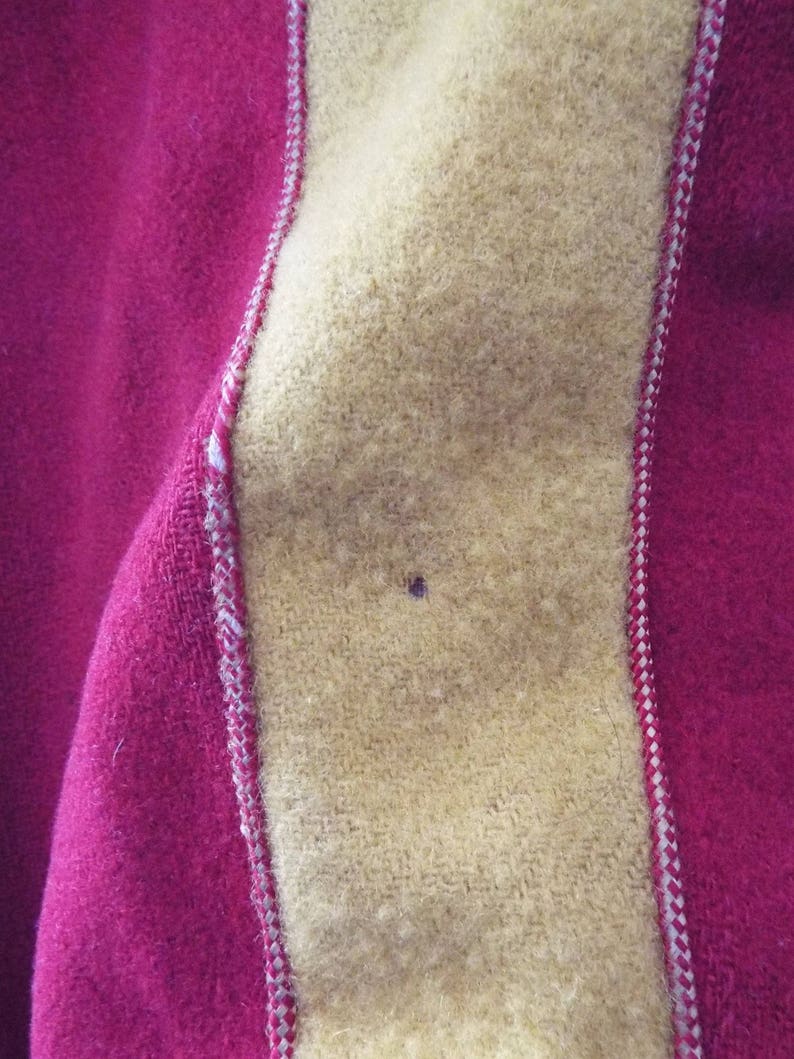 May include: Close-up of a red and yellow fabric with a white stitched seam. The fabric has a fuzzy texture.