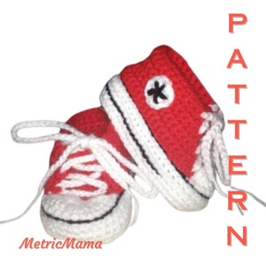 Puede incluir: Zapatos de bebé de ganchillo rojos con cordones blancos y una estrella negra en el lateral. Los zapatos están etiquetados como "PATTERN" en el lado derecho de la imagen.