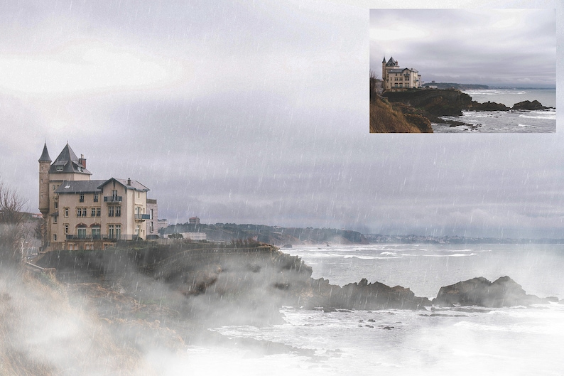 May include: A white building with a tower on a cliff overlooking a foggy ocean. The sky is gray and it is raining.