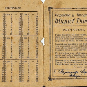 Puede incluir: Una tarjeta de papel amarillenta con una tabla de multiplicación vintage. La tabla muestra los hechos de multiplicación para los números del 1 al 10. La tarjeta también presenta un anuncio de texto para una papelería e imprenta llamada "Papeleria y Tipografia Miguel Duran". El anuncio incluye un poema en catalán sobre la llegada de la primavera.