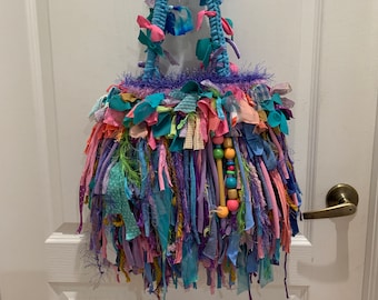 May include: A blue crocheted bag with a fringe of colourful fabric scraps and wooden beads. The bag has a blue crocheted strap.