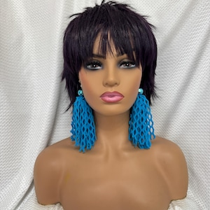 May include: A mannequin with short black hair wearing a pair of turquoise blue net earrings.