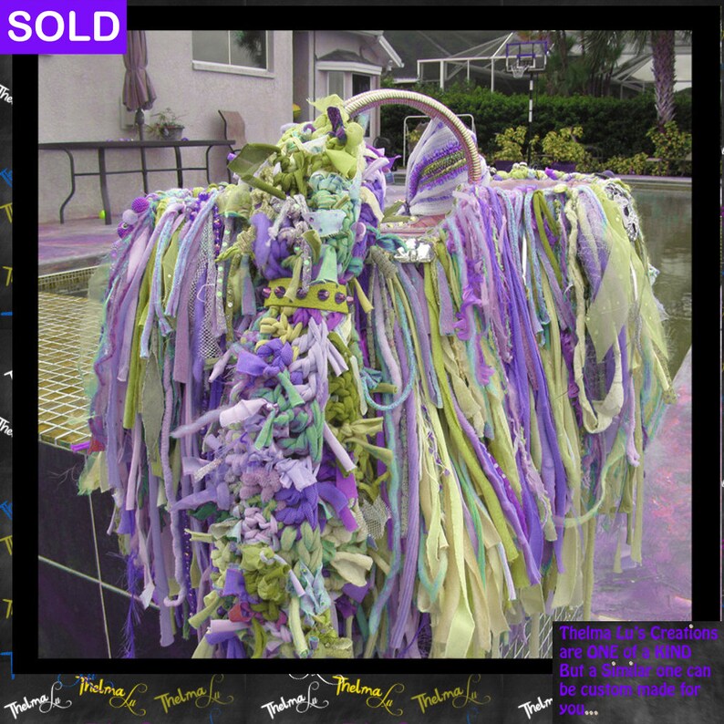May include: A purple, green, and white fabric handbag with a silver handle and a beaded embellishment. The bag is made of strips of fabric that are tied together. The text "Thelma Le's Creations are One of a Kind But a similar one can be custom made for you..." is visible at the bottom of the image.