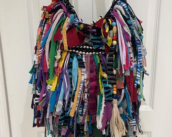 May include: A colourful, multi-textured, fringed tote bag with a black crocheted strap and beaded accents.