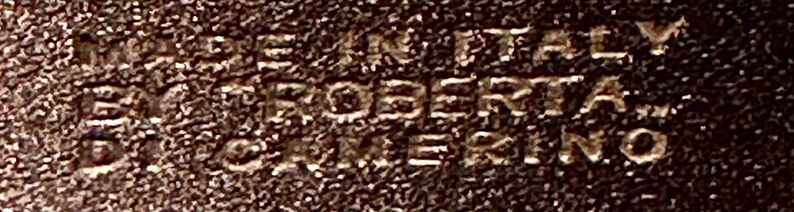 May include: Close-up of a brown leather tag with the text "PROPERTY OF KERNO" embossed in white.