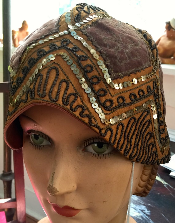A helmet cloche in golds,soutache,sequins, embroid