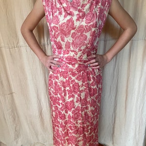 May include: A vintage sleeveless dress with a pink floral print on a cream background. The dress has a fitted bodice and a slightly flared skirt.