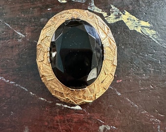 Brooch of gold metal and black faceted glass circa 1960s and has attachment for a pendant