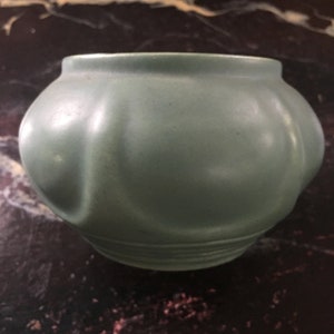 May include: A light green ceramic planter with a rounded, bulbous shape and a smooth, glossy finish.