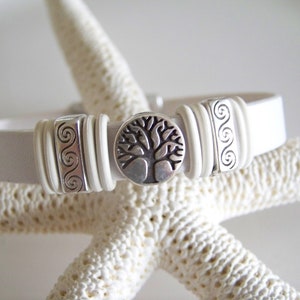May include: White leather bracelet with silver tone tree of life charm and swirl design accents.