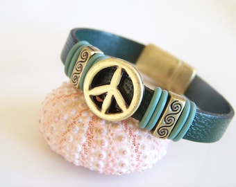 May include: A dark green leather bracelet with a peace sign charm and turquoise blue accents. The bracelet has a magnetic clasp.