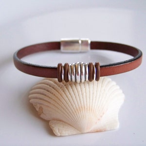 May include: A brown leather bracelet with a silver magnetic clasp and a silver and brown bead accent.