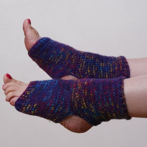 May include: A pair of knitted foot warmers in shades of purple, blue, red, and yellow. The open-toe design allows for comfort and flexibility. These foot warmers are ideal for yoga, pilates, or lounging at home.