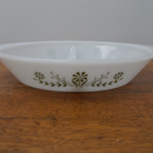 May include: White oval casserole dish with two handles. The dish features a floral design in olive green around the exterior. The dish is made of a durable, heat-resistant material, suitable for baking and serving.