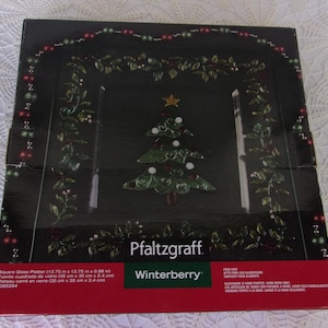 May include: A square glass platter with a Christmas tree design. The platter is black with a green and red Winterberry design. The platter measures 13.75 inches by 13.75 inches.